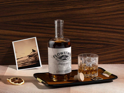 Flowstate whiskey displayed with and image of a surfer and dried fruit. 
