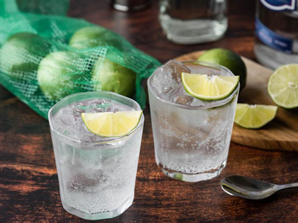 Two glasses of gin with fresh lime wedges. 