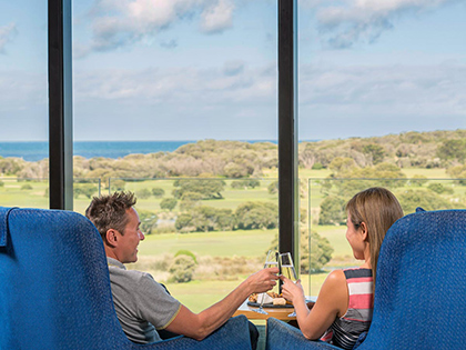 Couple sitting by floor to ceiling window having wine in Hardings Lounge at RACV Torquay Resort.