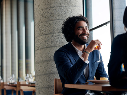 Man sitting in a restaurant holding a drink in his hand