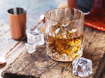 Whiskey glass with ice cubes placed next to the glass. 