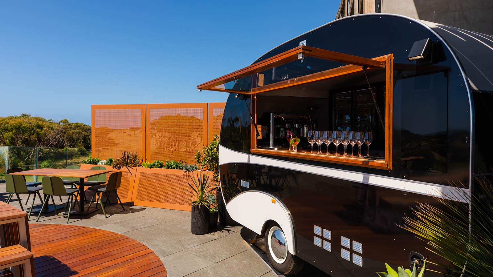 A black parked trailer at RACV Torquay Resort, set up as a bar with wine glasses lining the windowsill.