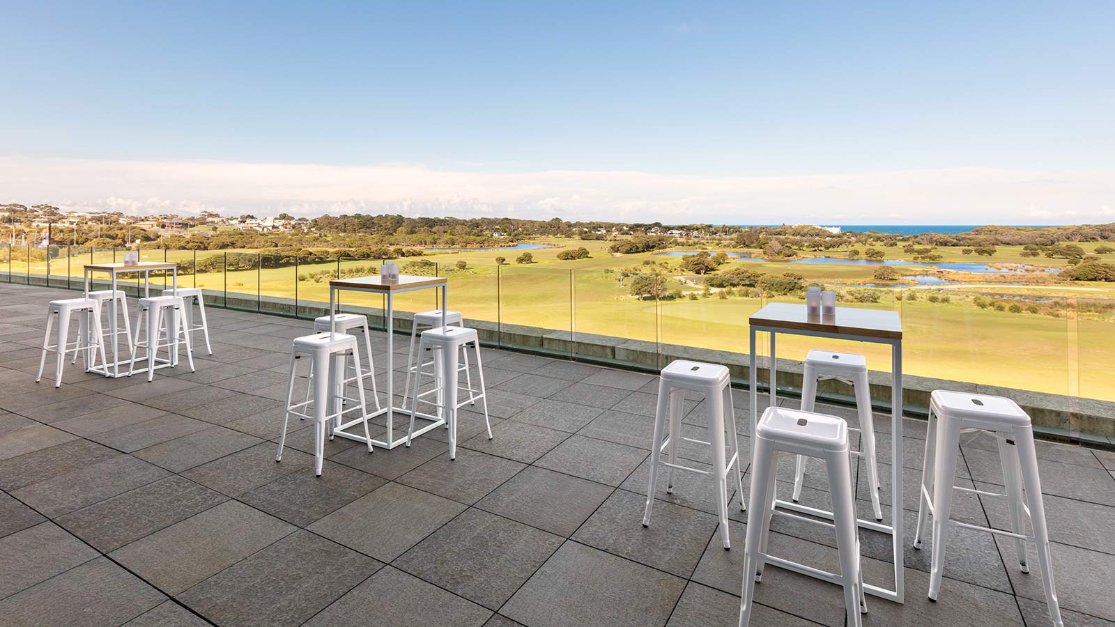 Outdoor terrace at RACV Torquay Resort, featuring bar stools and tables.