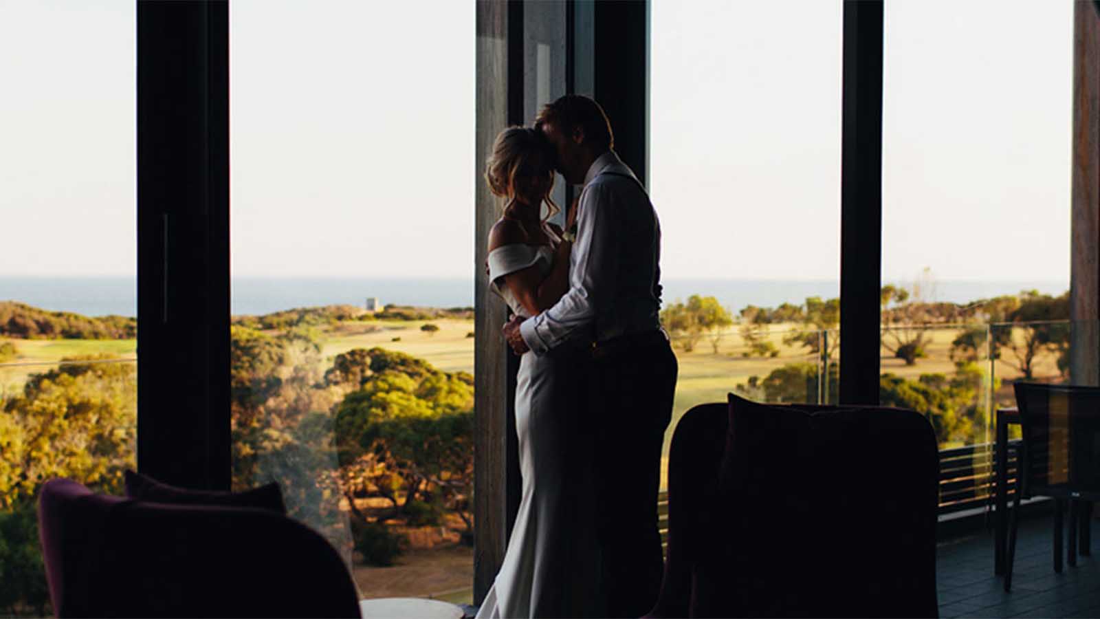 A bride and groom embracing in front of the Torquay golf course.