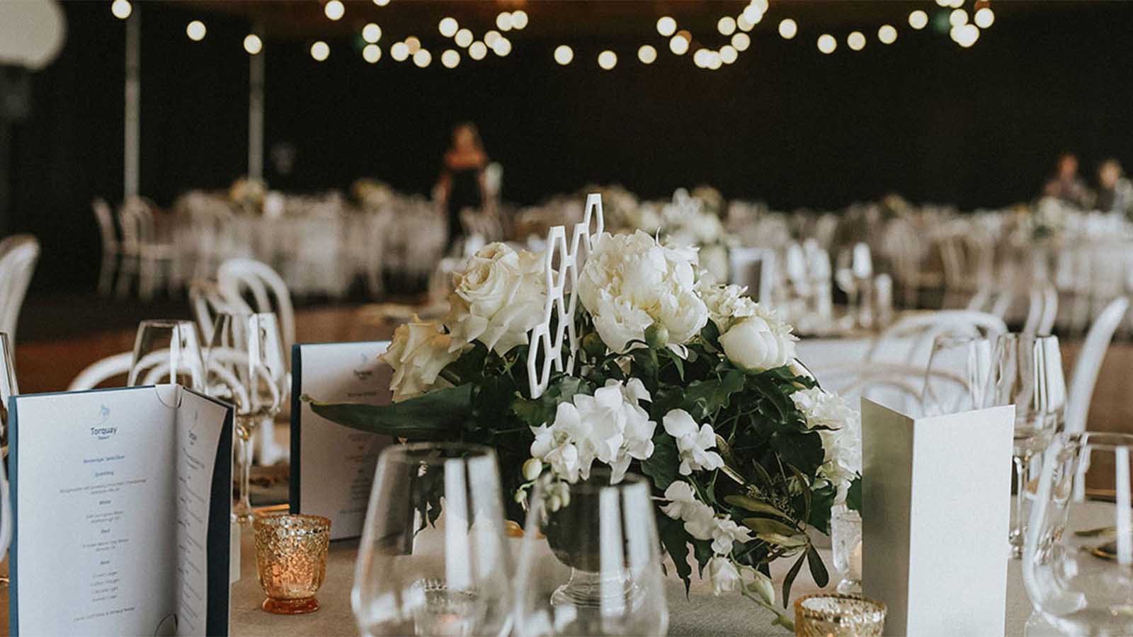 Table setting including flowers, menus, glassware and candles for a Torquay wedding reception.