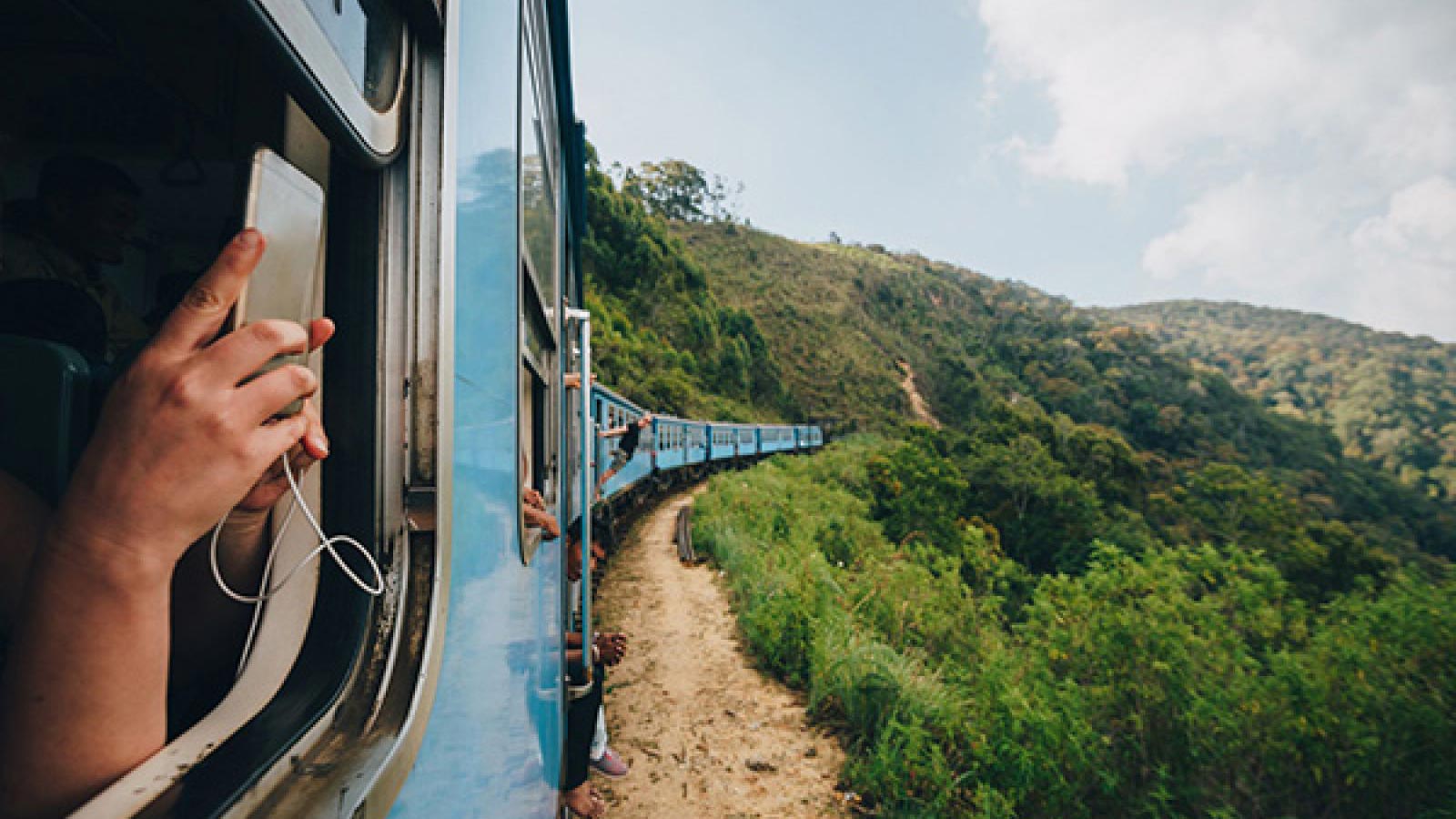 Someone taking a scenic photo out of the window of a blue train.