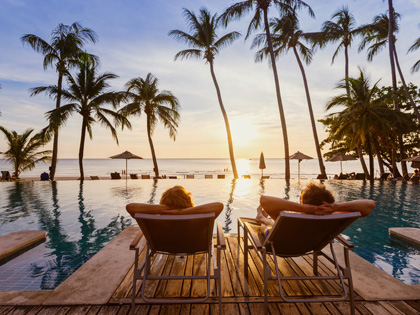 People lounging at a hotel pool in the sunset