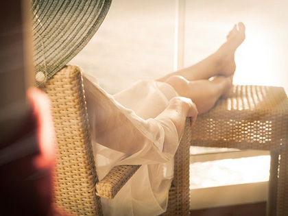 Woman lounging with her legs up on a sunny seat.