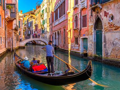 Narrow canal with gondola and bridge in Venice, Italy