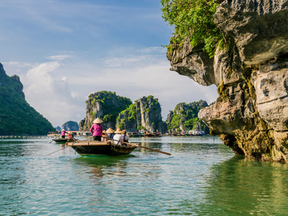 Tourists enjoying a boat trip with local guides through the majestic limestone mountains of Halong bay, Vietnam