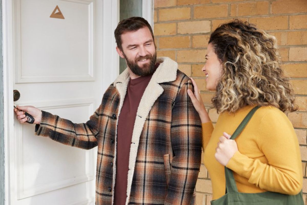 man locking front door with woman talking to him