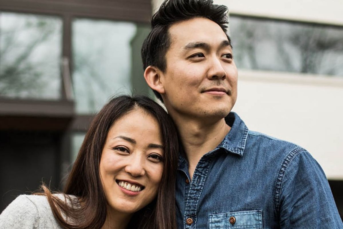 portrait shot of a couple standing together outside a home