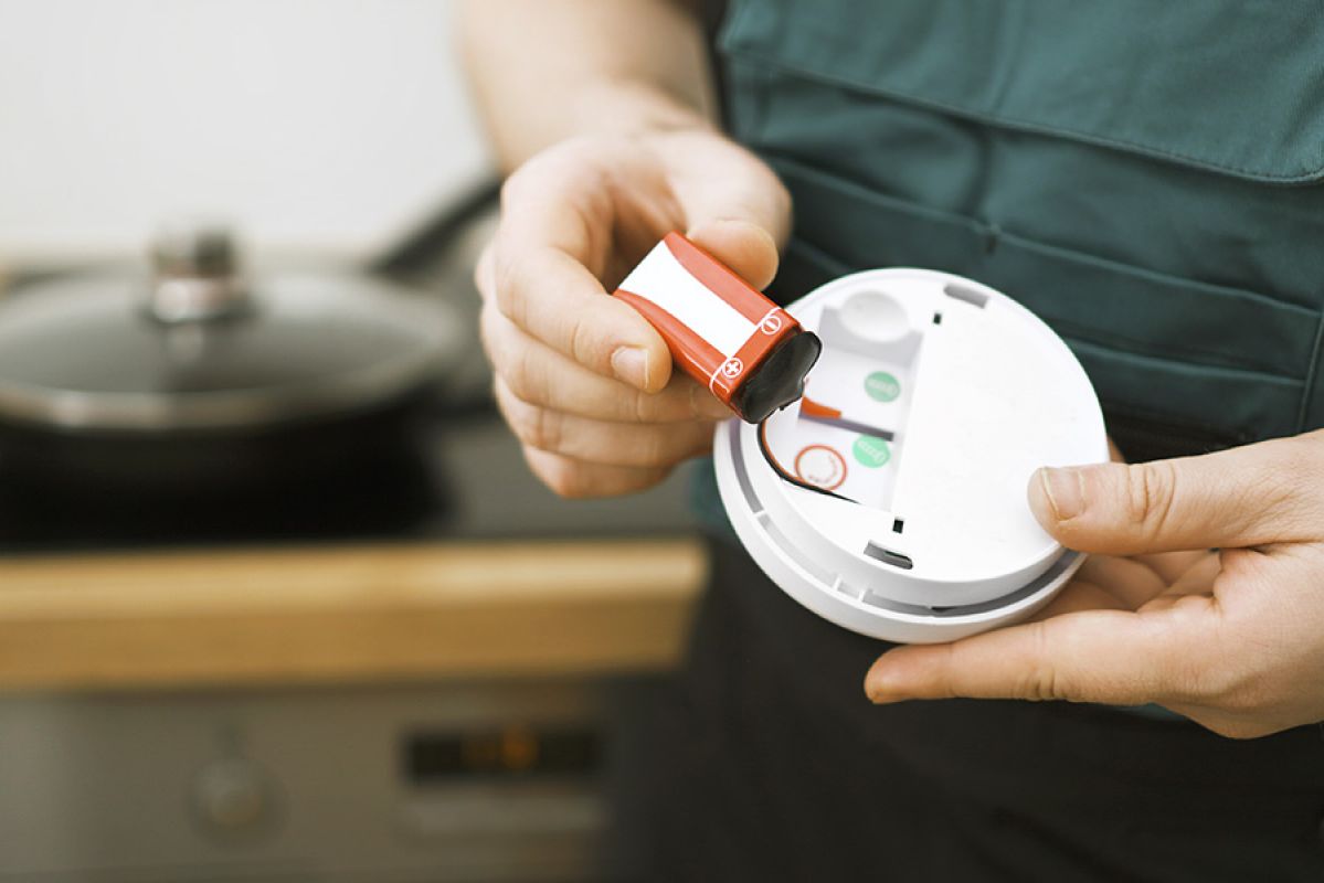 Man changing smoke alarm battery in the kitchen.