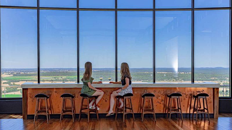 Two women sitting in front of large window at winery