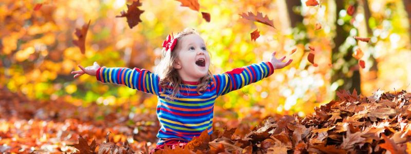 girl throwing autumn leaves