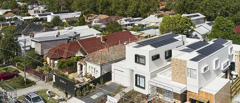 Exterior view of Fairfield House fitted with solar panels, with the Melbourne CBD cityscape in the background. 