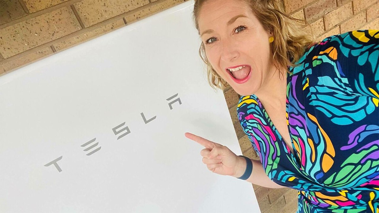 tesla-happy-customer-1600x900.jpg Smiling customer pointing at a Tesla battery.