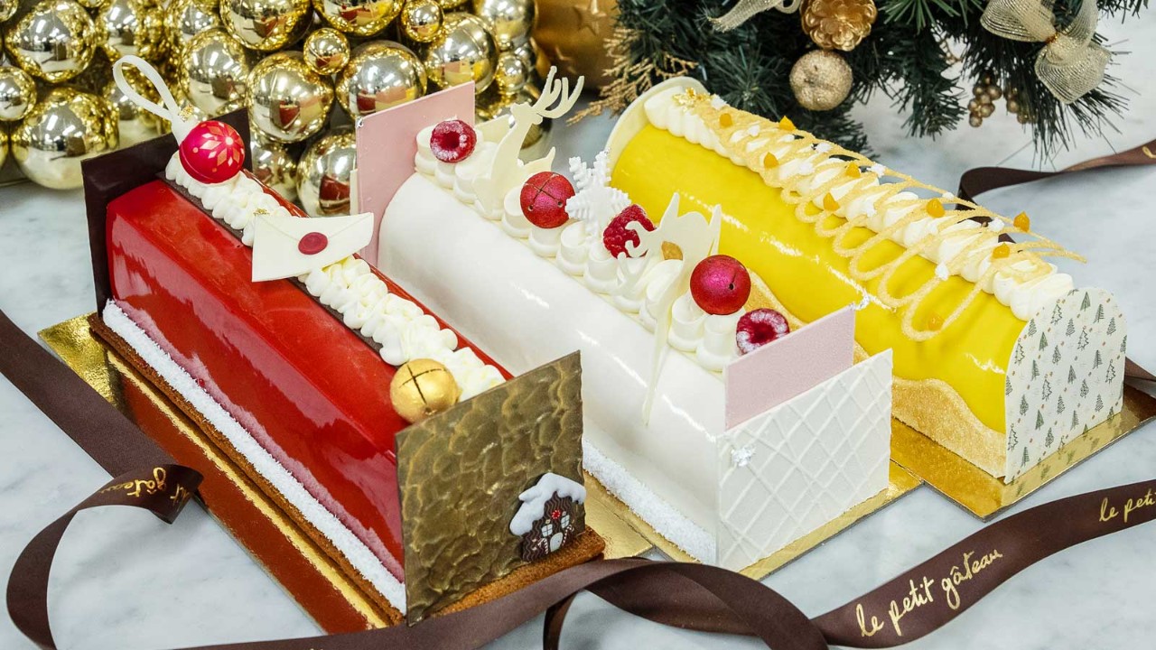 Three Christmas Yule logs decorated and surrounded by Christmas decor.