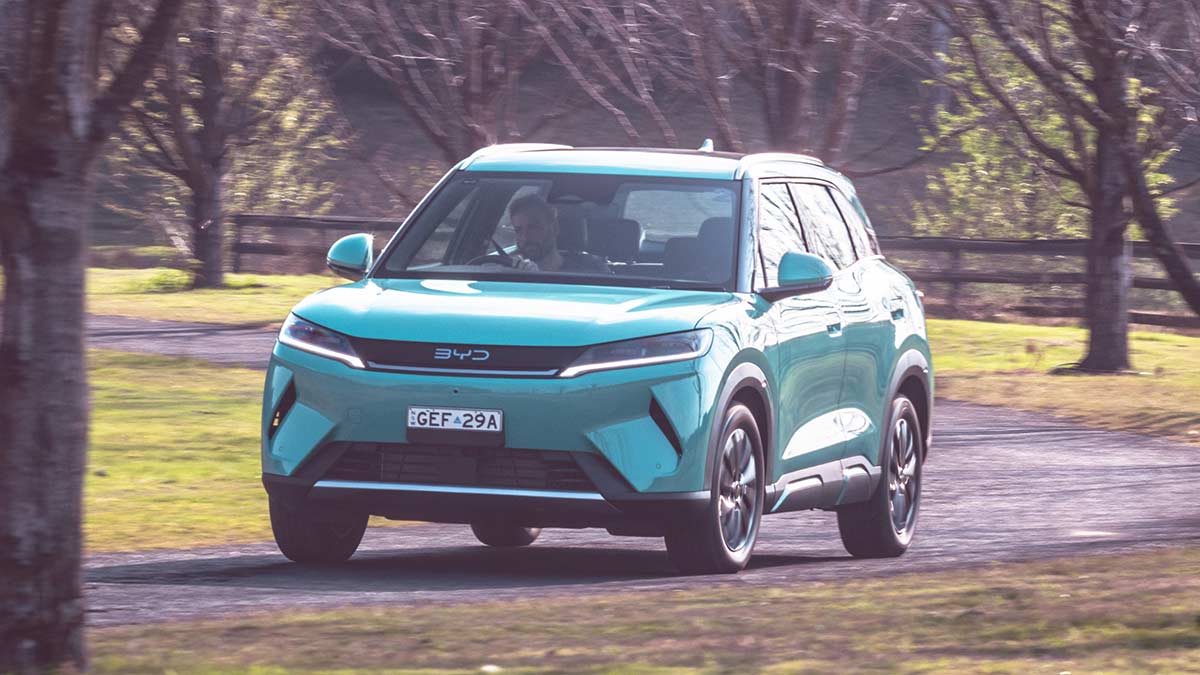 A BYD Atto 2 DM-i takes a bend in the road with its lights on 