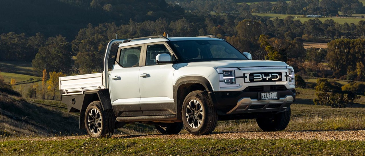 White BYD Shark 6 Dynamic Cab Chassis dual cab ute on gravel track on hilly rural property.