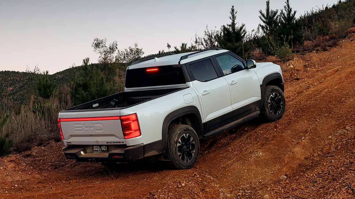 White BYD Shark 6 Performance ute at base of steep red-earth off-road track.