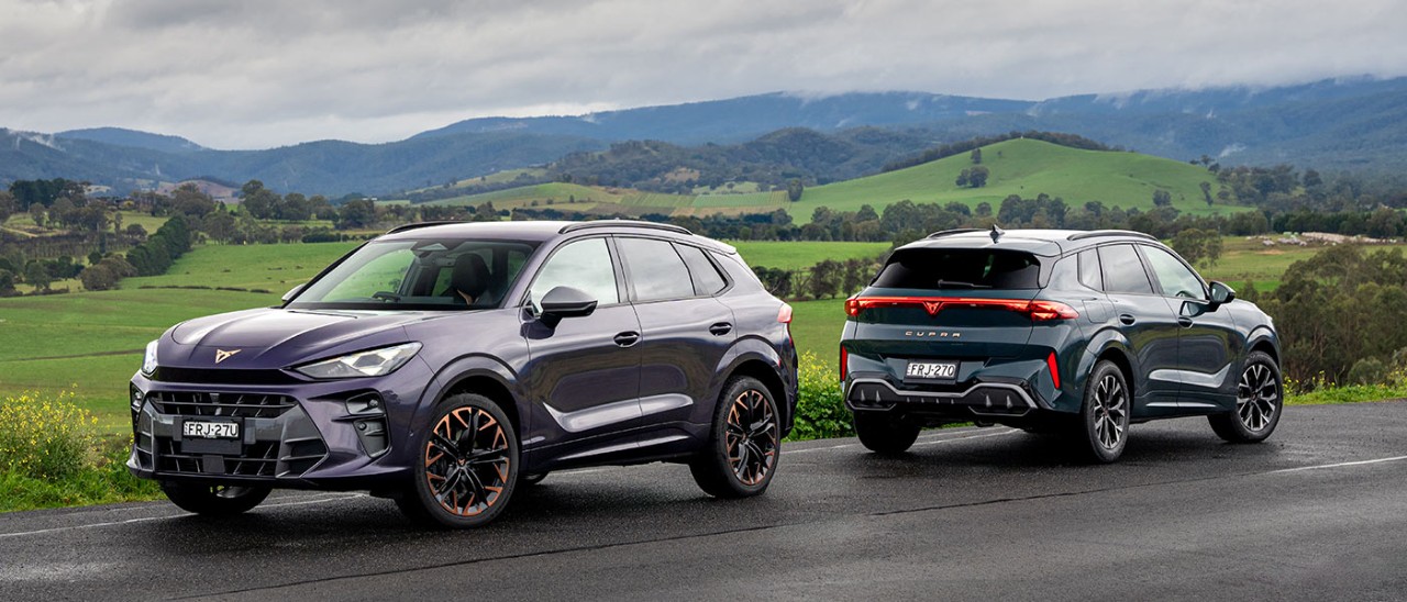 Purple Cupra Terramar VZ and blue Terramar S medium SUVs on country road with green rolling hills behind.