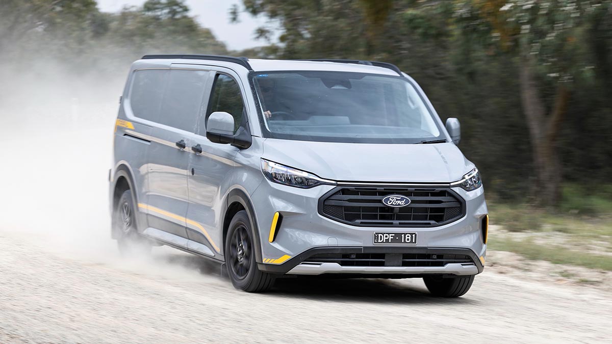 Silver-coloured Ford Transit Custom Trail driving on dusty dirt road.