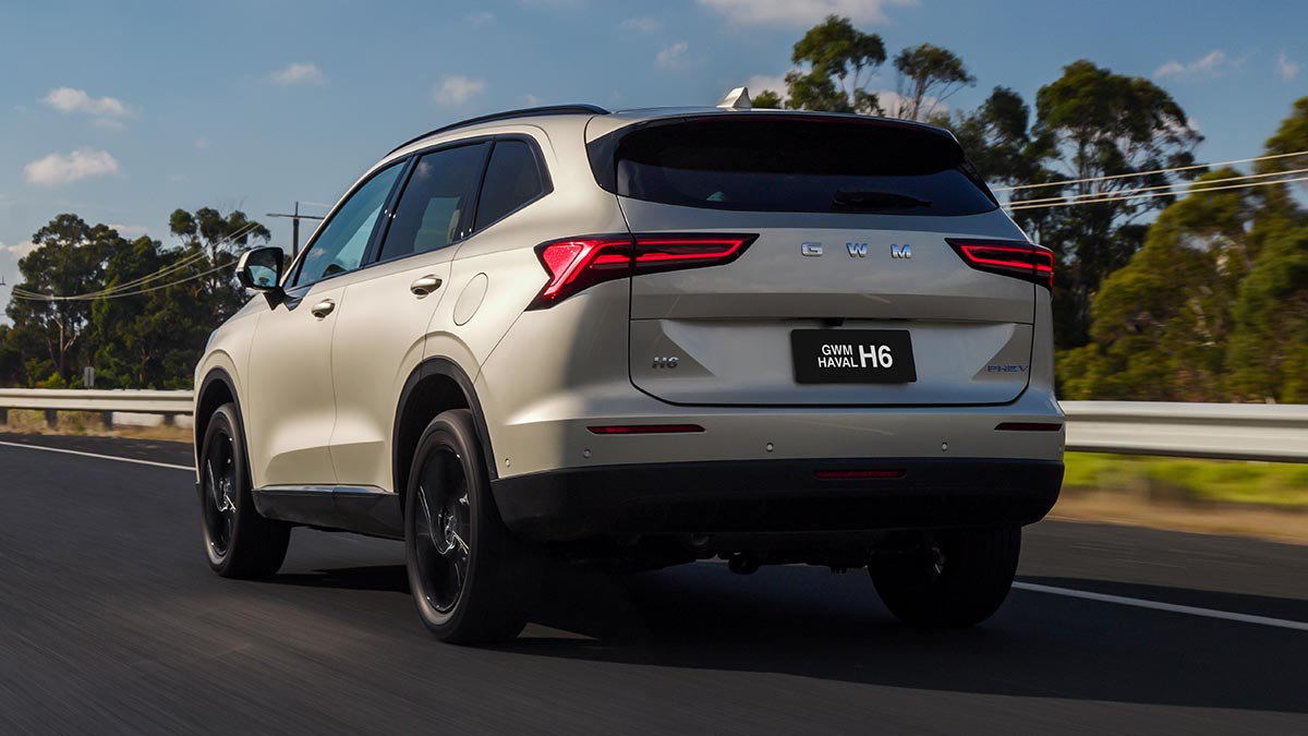 Rear view of pearl-coloured GWM Haval H6 plug-in hybrid SUV on dual-lane highway in country Victoria.