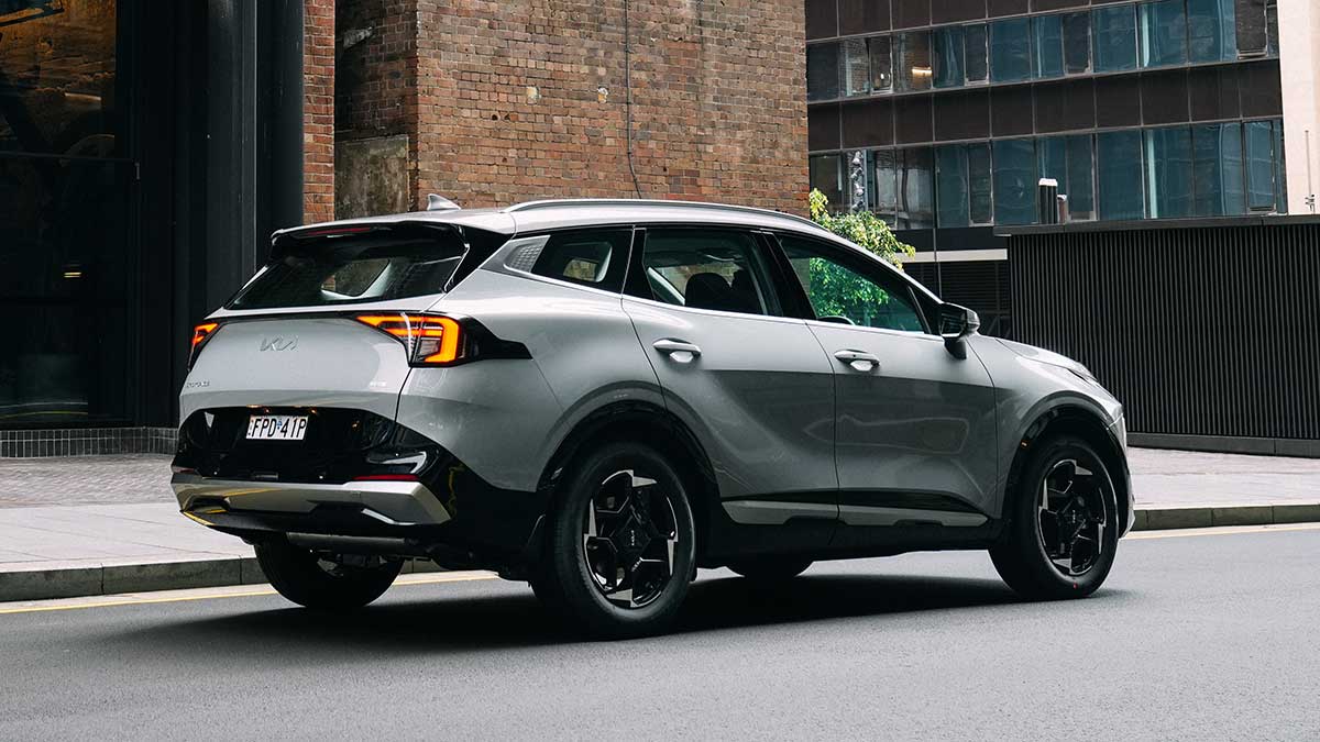 Rear view of white Kia Sportage SX Hybrid SUV parked on street in urban industrial area