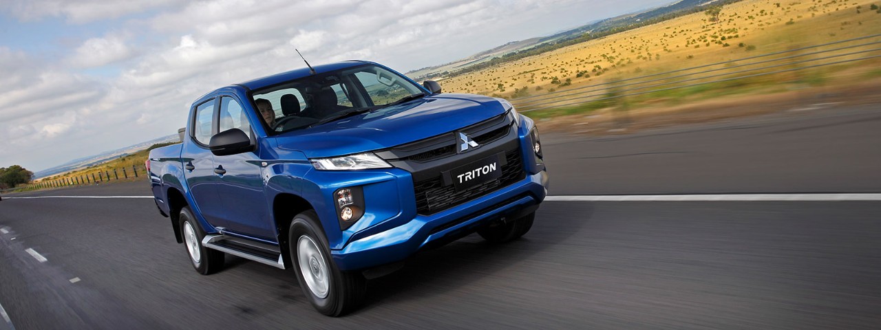 Front side angled view of a blue Mitsubishi Triton in motion