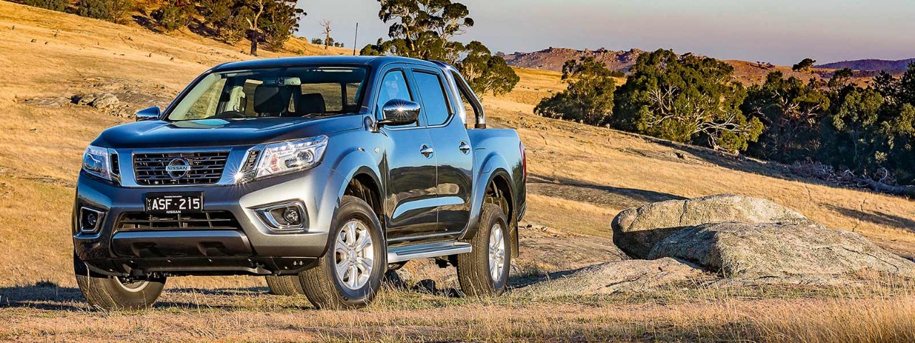 Front side view of a dark grey Nissan Navara 2018 car parked in a field