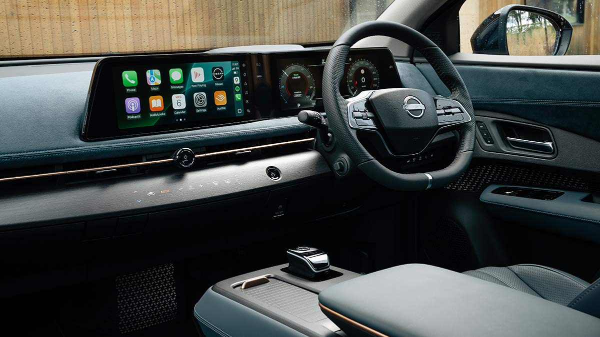 Dual screens and blue suede-type material across dashboard of Nissan Ariya Evolve electric SUV. 