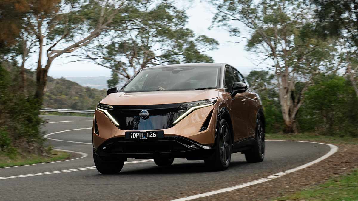 Copper-coloured Nissan Ariya Evolve electric SUV driving up winding road on Victoria’s Mornington Peninsula. 