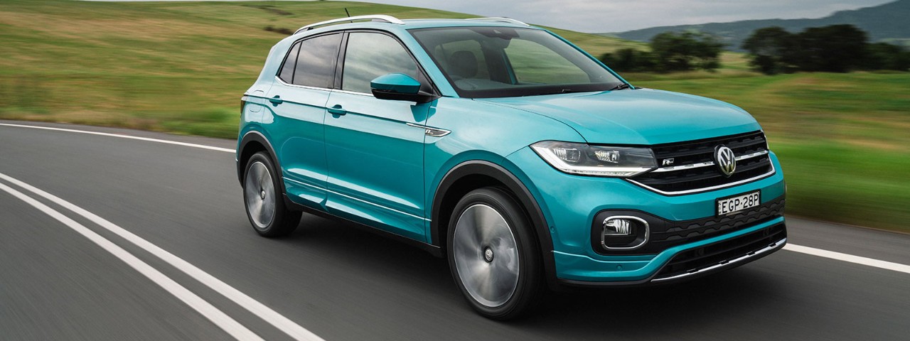Front side view of a turquoise Volkswagen T-Cross 85 TSI Style 2020 car in motion on a road