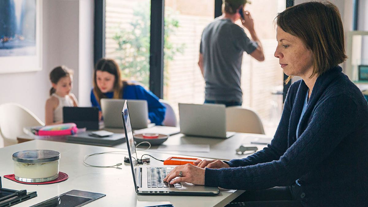 woman sitting at desk in front of laptop and calculator and documents