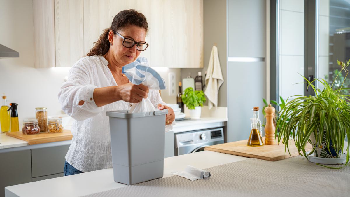 woman emptying food scraps bin in kitchen
