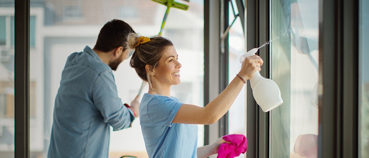 Couple cleaning windows in apartment