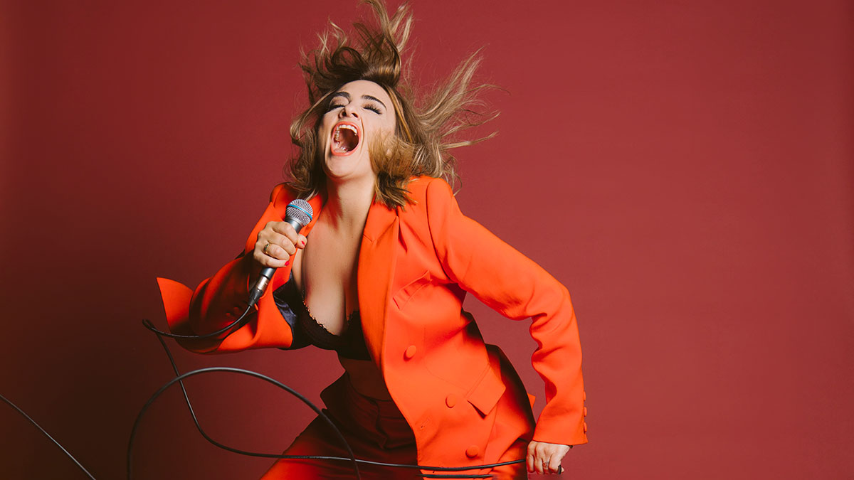 Singer in orange suit belting out a rock song