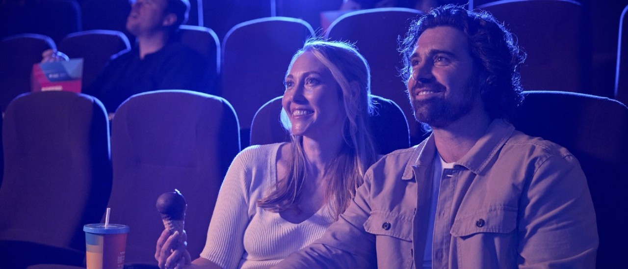 A man and woman enjoying a film in a darkened theatre with choc tops and popcorn