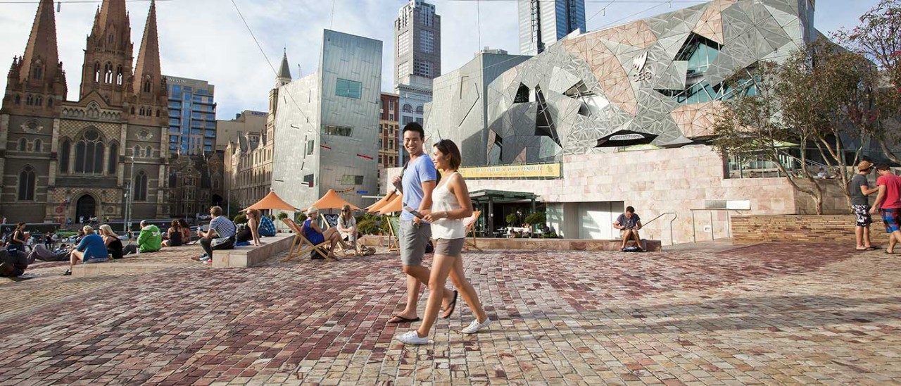 Couple walking through Federation Square in Melbourne.