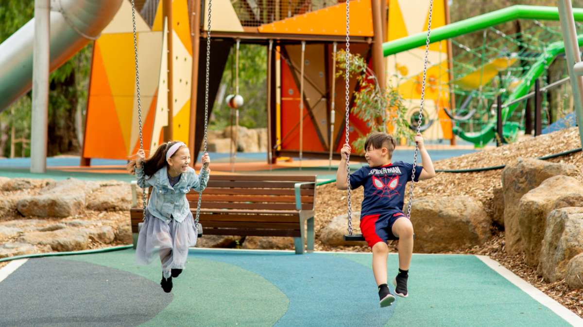 Two children playing on swings at Wyndham Park in Werribee