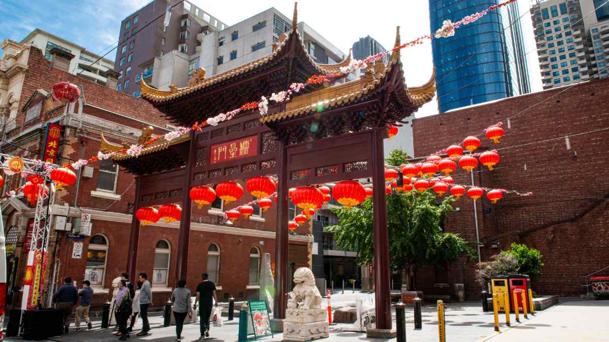 people walking through traditional Chinese archway decorated with red lanterns