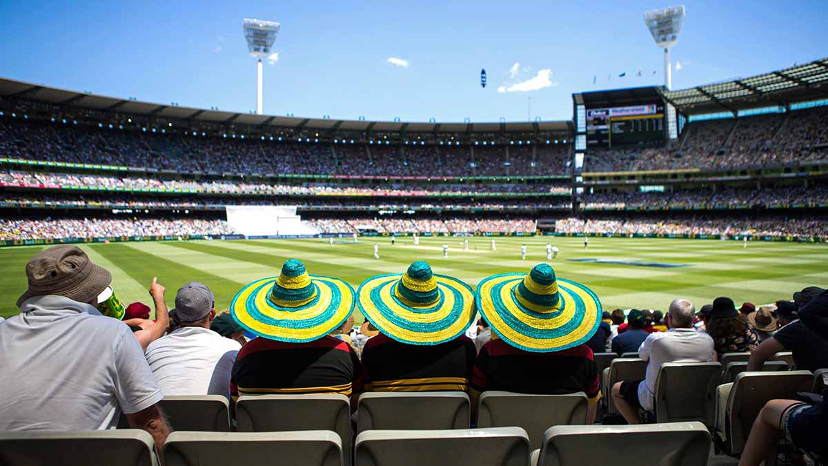 Three cricket fans wearing green and yellow sombreros at MCG in Melbourne.