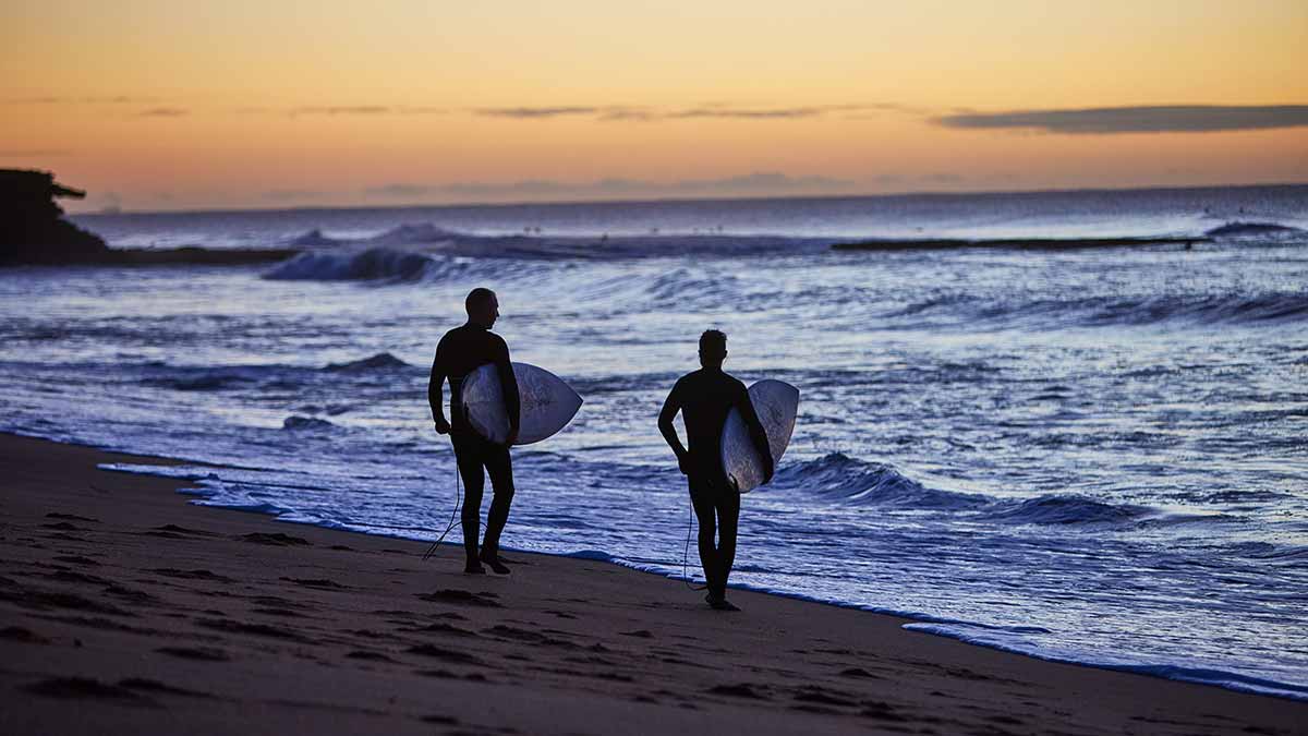 Two surfers carrying surf boards at Bells Beach in Victoria.