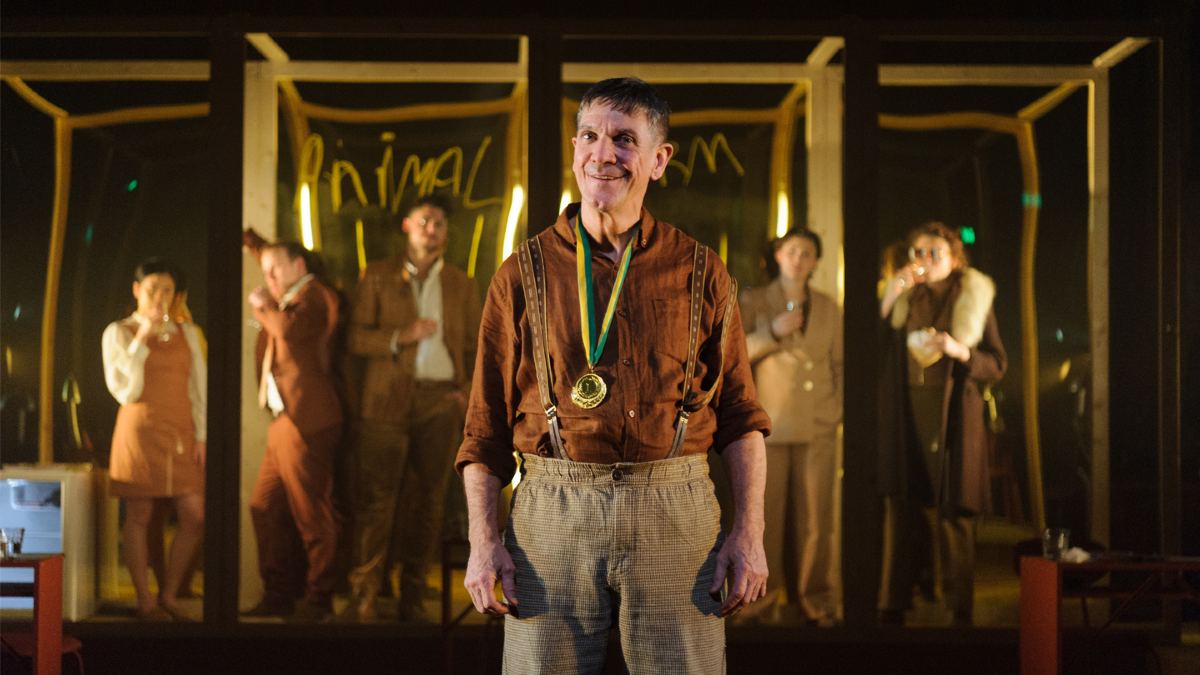 actors dressed as farmers onstage; forefront is a middle-aged man wearing a medal