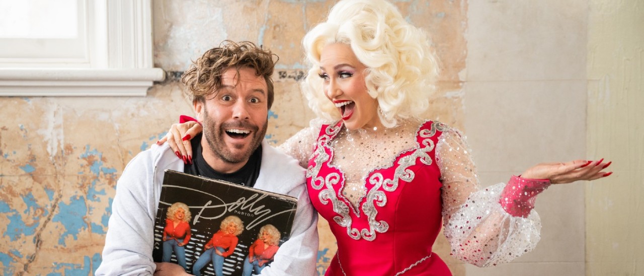 young man holding a Dolly Parton record being hugged by Dolly