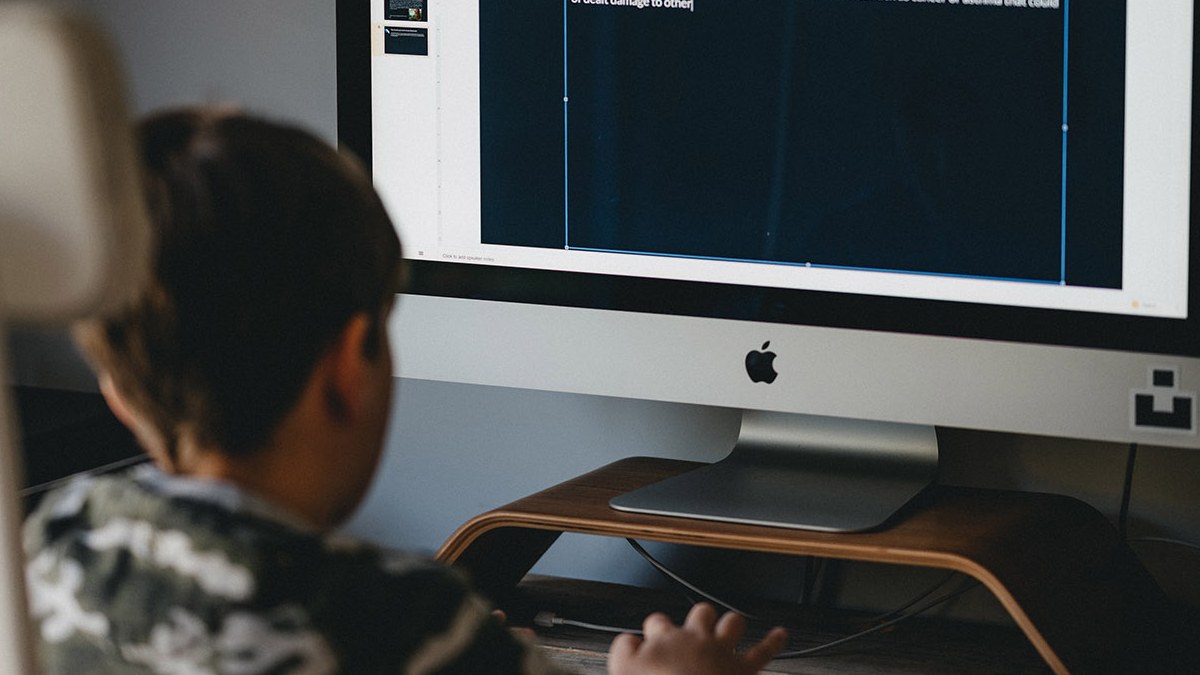 child typing at desktop computer and looking into screen