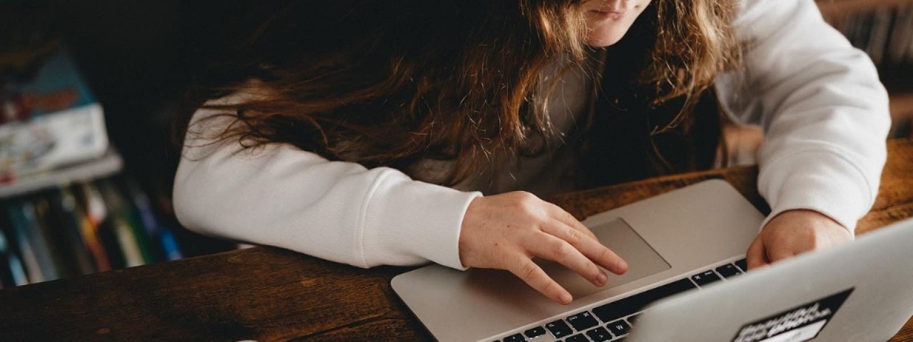 child with long hair working on a laptop