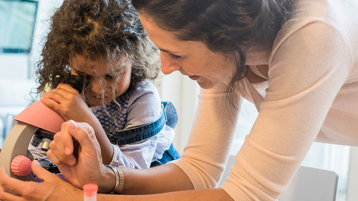 adult and child looking in to microscope on table