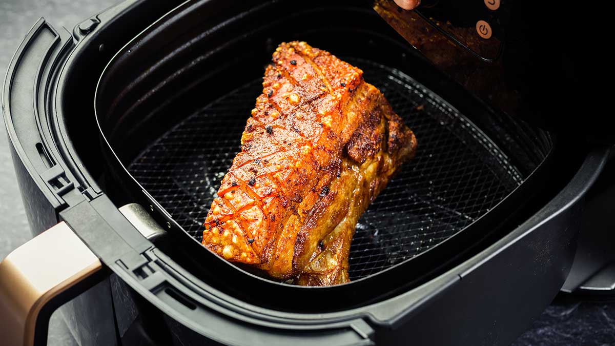Piece of cooked pork belly in an air fryer drawer.